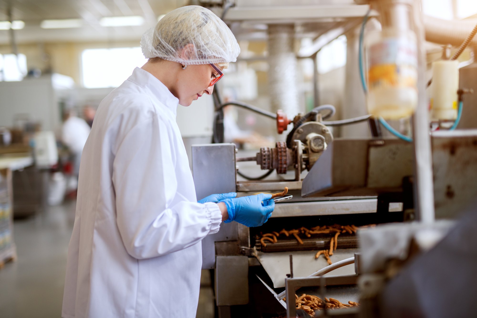 gros plan-jeune-femme-travailleuse-corvée-tissu-stérile-inspectant-bâtonnets-de-sel-pris-dans-la-ligne-de-production-de-nourriture-snack gros plan-jeune-femme-travailleuse-corvée-tissu-stérile-inspectant-bâtonnets-de-sel-pris-dans-la-ligne-de-production-de-nourriture-snack